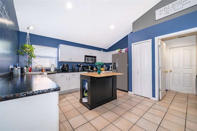 kitchen featuring light tile patterned flooring, appliances with stainless steel finishes, a center island, white cabinets, and wood counters