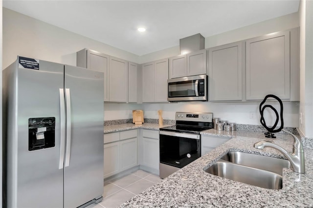 kitchen featuring light tile patterned floors, sink, light stone counters, and appliances with stainless steel finishes