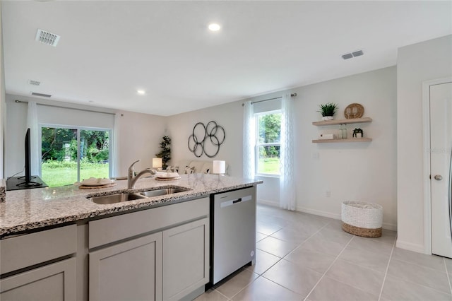 kitchen with stainless steel dishwasher, a healthy amount of sunlight, sink, and light stone counters