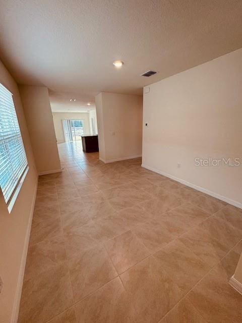 unfurnished room featuring visible vents, a textured ceiling, and baseboards