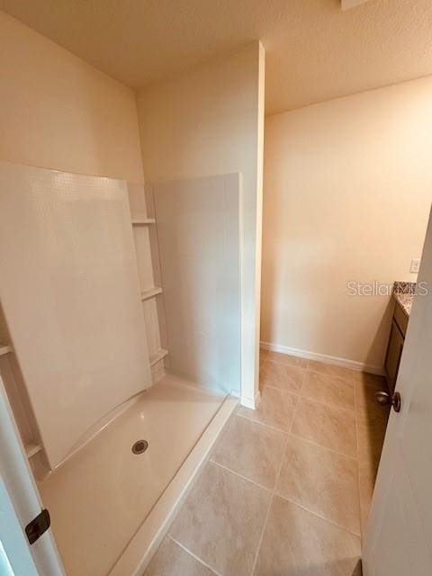 bathroom with tile patterned flooring, walk in shower, vanity, and baseboards