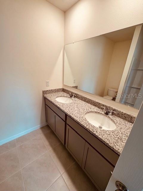 full bathroom with toilet, tile patterned flooring, double vanity, and a sink