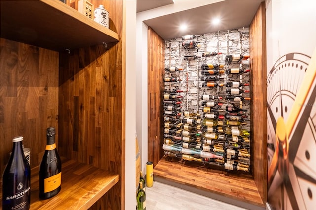 wine area with light hardwood / wood-style floors and wooden walls