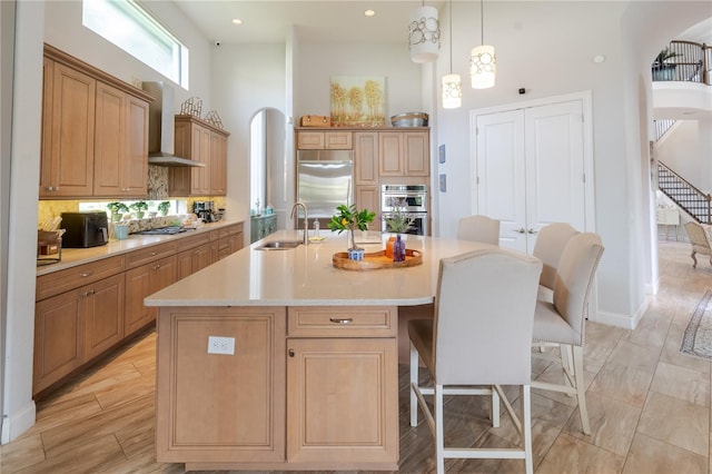 kitchen featuring appliances with stainless steel finishes, a center island with sink, decorative light fixtures, and sink