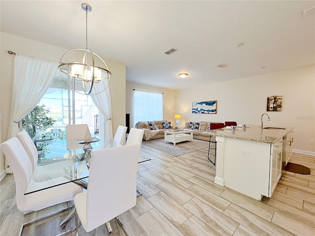 dining space with a chandelier, light hardwood / wood-style flooring, and sink