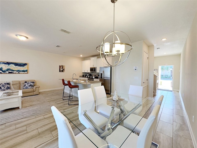 dining room with light wood-type flooring, sink, and a chandelier