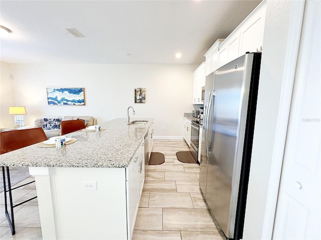 kitchen with sink, stainless steel appliances, a kitchen breakfast bar, an island with sink, and white cabinets