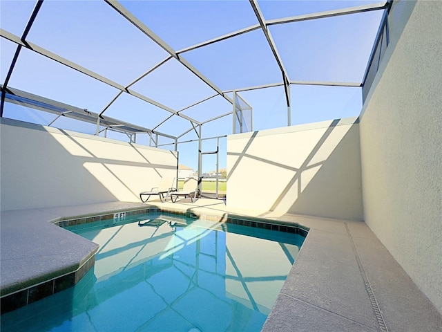 view of swimming pool featuring glass enclosure and a patio area