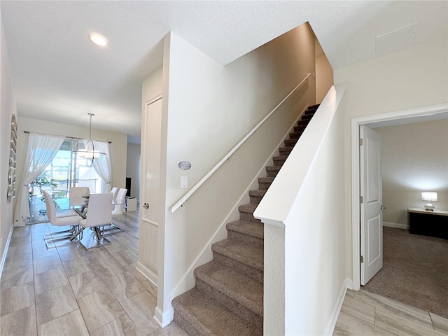 stairs with carpet flooring and a notable chandelier