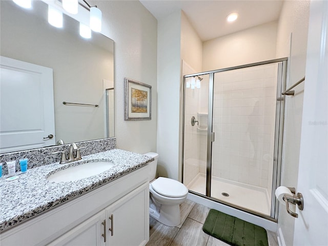 bathroom featuring hardwood / wood-style floors, vanity, toilet, and a shower with shower door