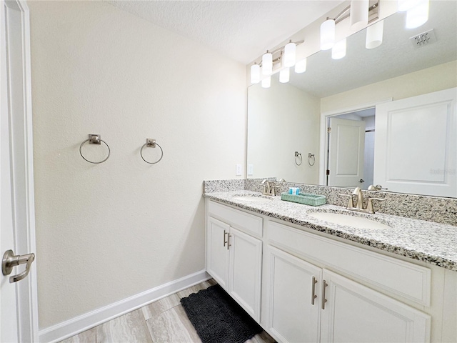 bathroom with hardwood / wood-style flooring, vanity, and a textured ceiling