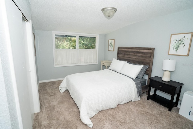 bedroom with a textured ceiling, light colored carpet, and a closet