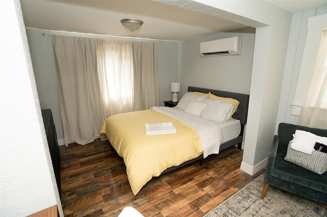 bedroom with a wall mounted AC and dark wood-type flooring