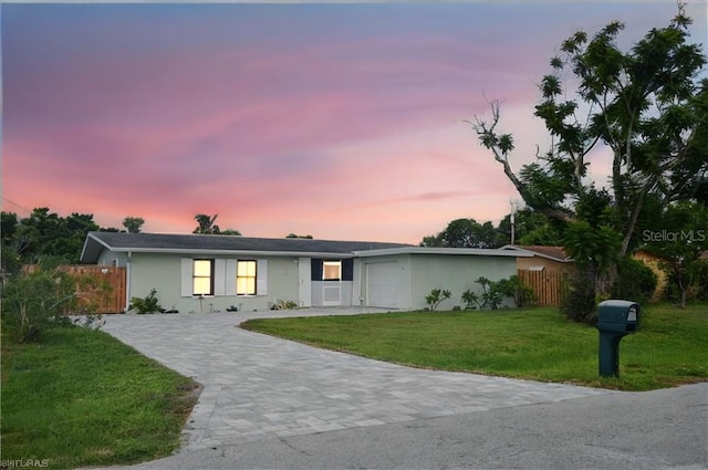 ranch-style house with a garage and a yard