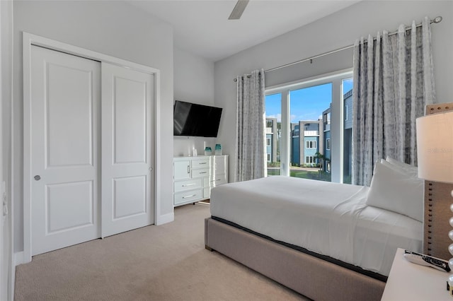 bedroom with a closet, light carpet, and ceiling fan