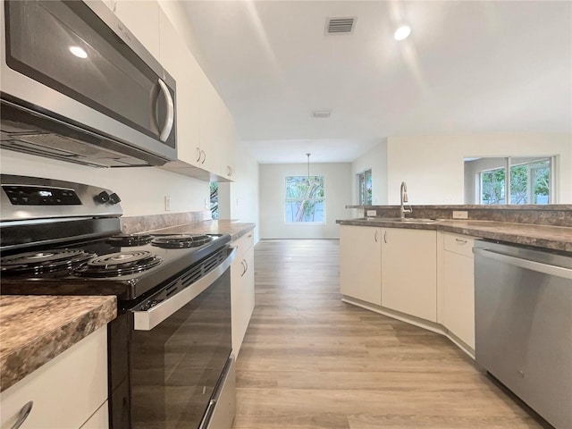 kitchen with white cabinets, a wealth of natural light, stainless steel appliances, and light hardwood / wood-style floors