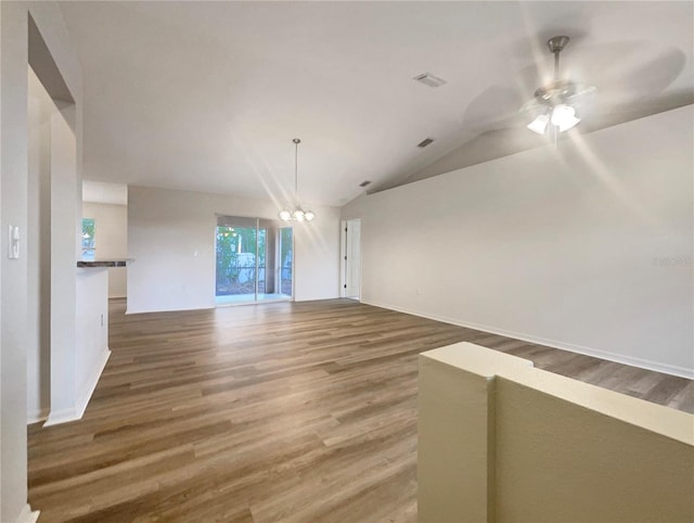 unfurnished room featuring wood-type flooring, ceiling fan with notable chandelier, and vaulted ceiling