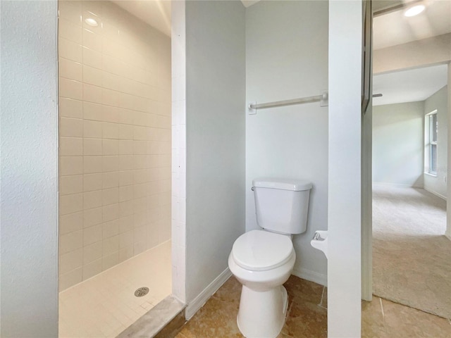 bathroom featuring tile patterned floors, toilet, and a tile shower