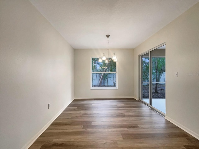 unfurnished dining area featuring dark hardwood / wood-style flooring and a notable chandelier