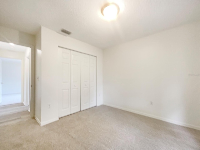 unfurnished bedroom featuring a closet and light colored carpet