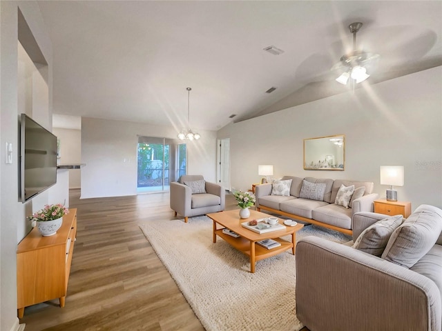 living room featuring hardwood / wood-style floors, ceiling fan with notable chandelier, and vaulted ceiling