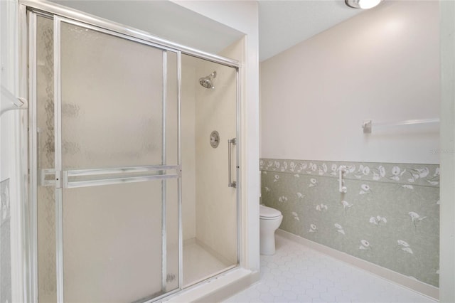 bathroom with a shower with door, tile patterned flooring, and toilet