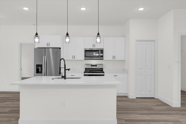 kitchen with stainless steel appliances, sink, decorative light fixtures, white cabinetry, and a kitchen island with sink