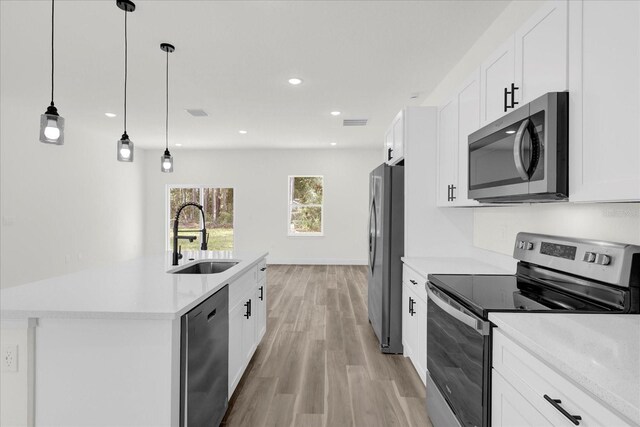 kitchen with sink, stainless steel appliances, white cabinets, and decorative light fixtures