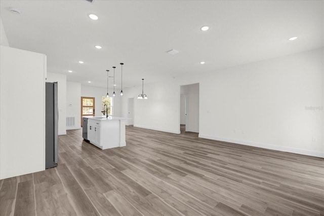 kitchen featuring light hardwood / wood-style floors, a center island, pendant lighting, sink, and white cabinetry