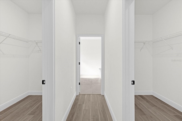 walk in closet with light hardwood / wood-style flooring