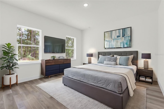 bedroom with light hardwood / wood-style floors and multiple windows