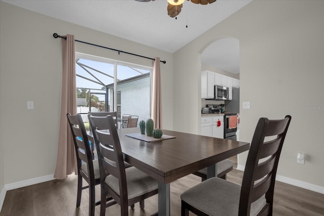 dining space featuring dark wood-type flooring, lofted ceiling, a textured ceiling, and ceiling fan