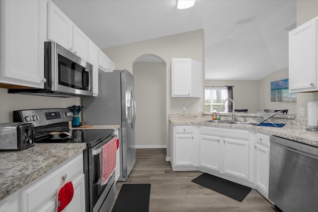 kitchen featuring vaulted ceiling, white cabinetry, and appliances with stainless steel finishes