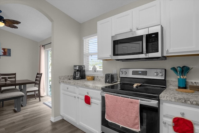 kitchen featuring hardwood / wood-style floors, appliances with stainless steel finishes, vaulted ceiling, and white cabinets