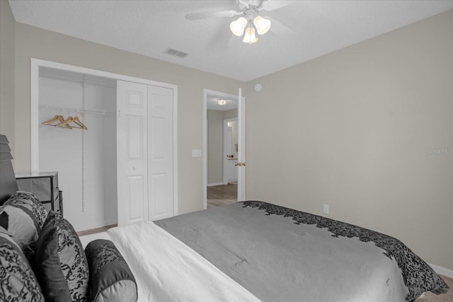 bedroom featuring a textured ceiling, light hardwood / wood-style flooring, ceiling fan, and a closet