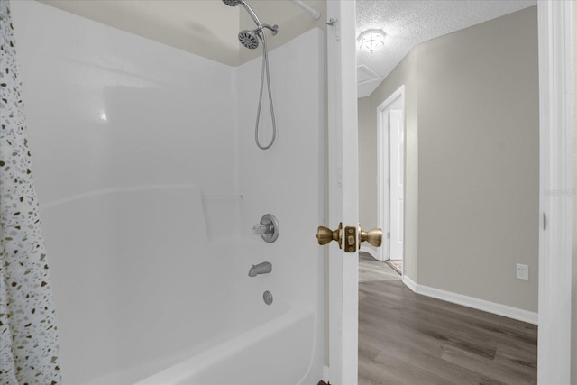 bathroom with shower / bath combination, wood-type flooring, and a textured ceiling