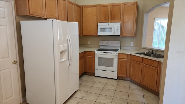 kitchen featuring sink, light tile patterned floors, and white appliances