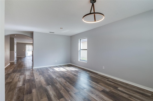 empty room with plenty of natural light and dark hardwood / wood-style floors