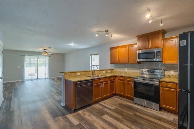 kitchen with sink, stainless steel appliances, kitchen peninsula, and dark wood-type flooring