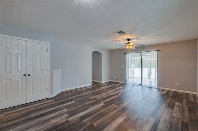 empty room featuring ceiling fan, dark wood-type flooring, and a textured ceiling