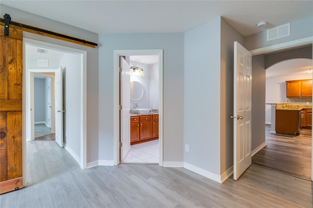 hallway with a barn door and light hardwood / wood-style floors