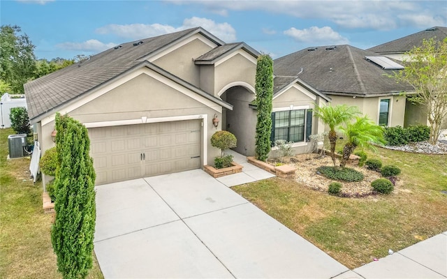 view of front of home with a garage, central AC unit, and a front yard