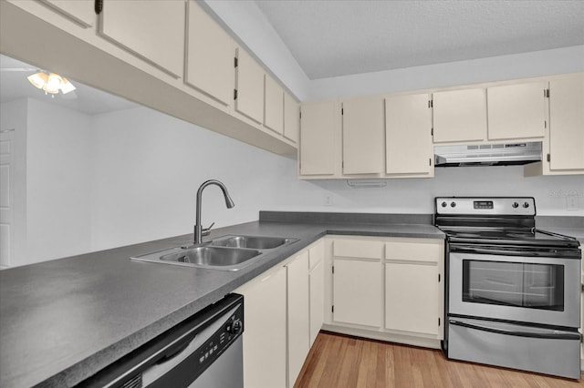 kitchen with light hardwood / wood-style floors, cream cabinets, a textured ceiling, sink, and appliances with stainless steel finishes