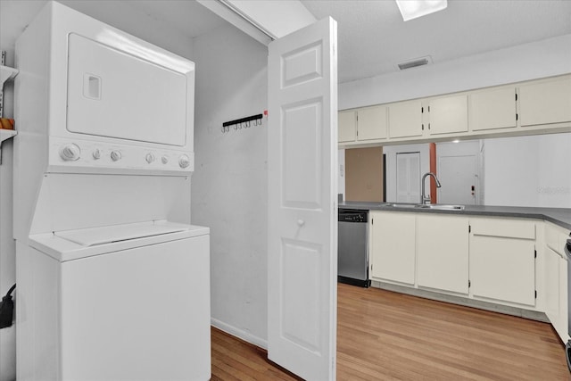 laundry room featuring stacked washing maching and dryer, sink, and light hardwood / wood-style floors