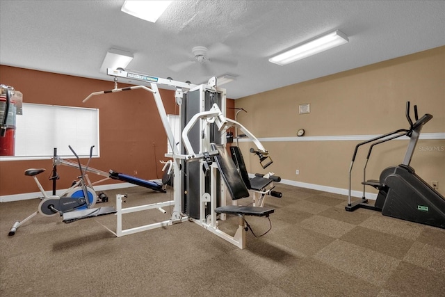 exercise area featuring carpet flooring, a textured ceiling, and ceiling fan