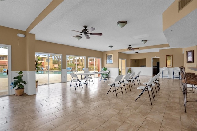 dining space featuring ceiling fan and a textured ceiling