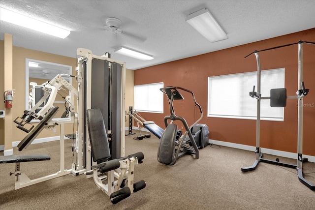 exercise area with ceiling fan and a textured ceiling