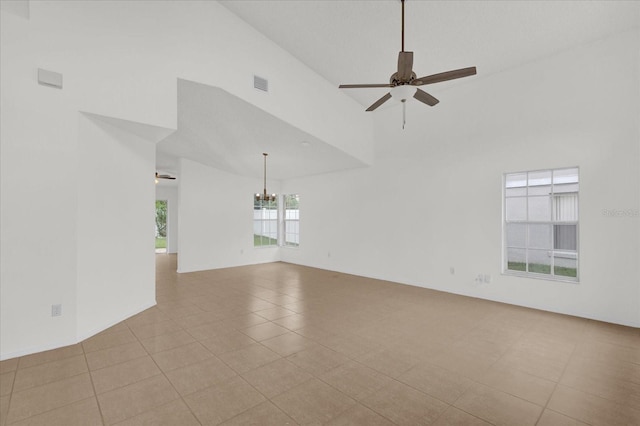 tiled spare room featuring high vaulted ceiling and ceiling fan with notable chandelier