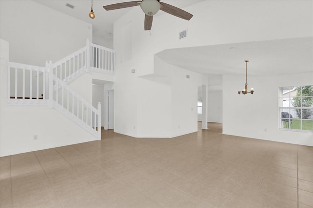 unfurnished living room featuring ceiling fan with notable chandelier and a high ceiling