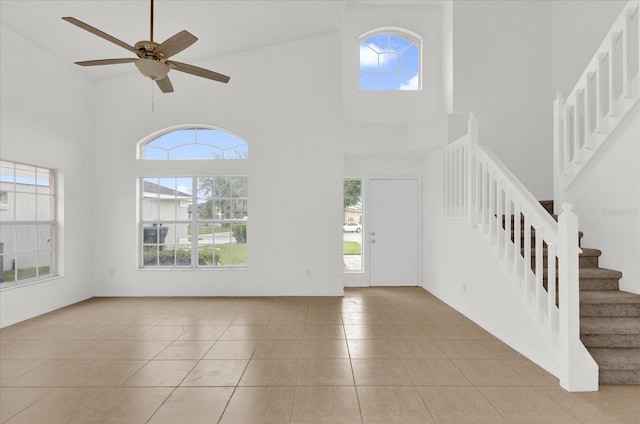 tiled foyer entrance with ceiling fan, a healthy amount of sunlight, and high vaulted ceiling